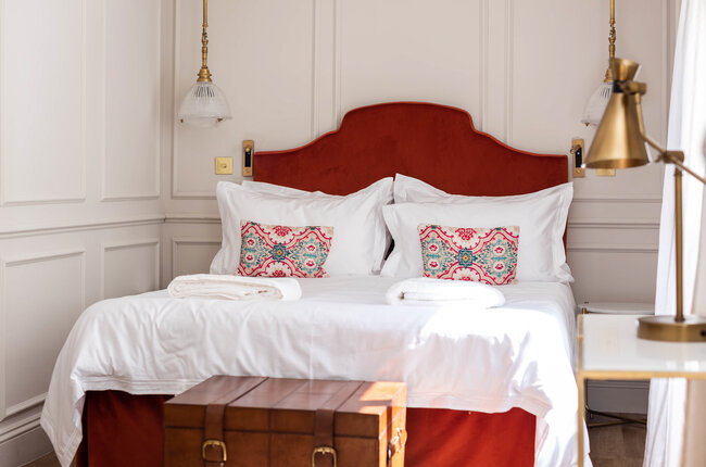 A large king size bed with red cushions on it at one of the MyHolidayLetBrighton properties.